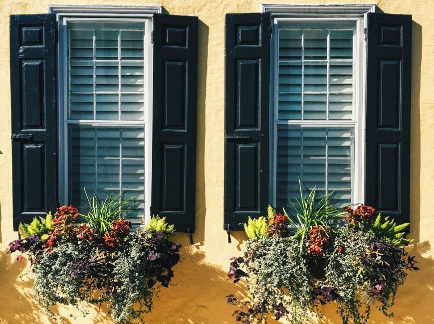 yellow house with black shutters and window boxes