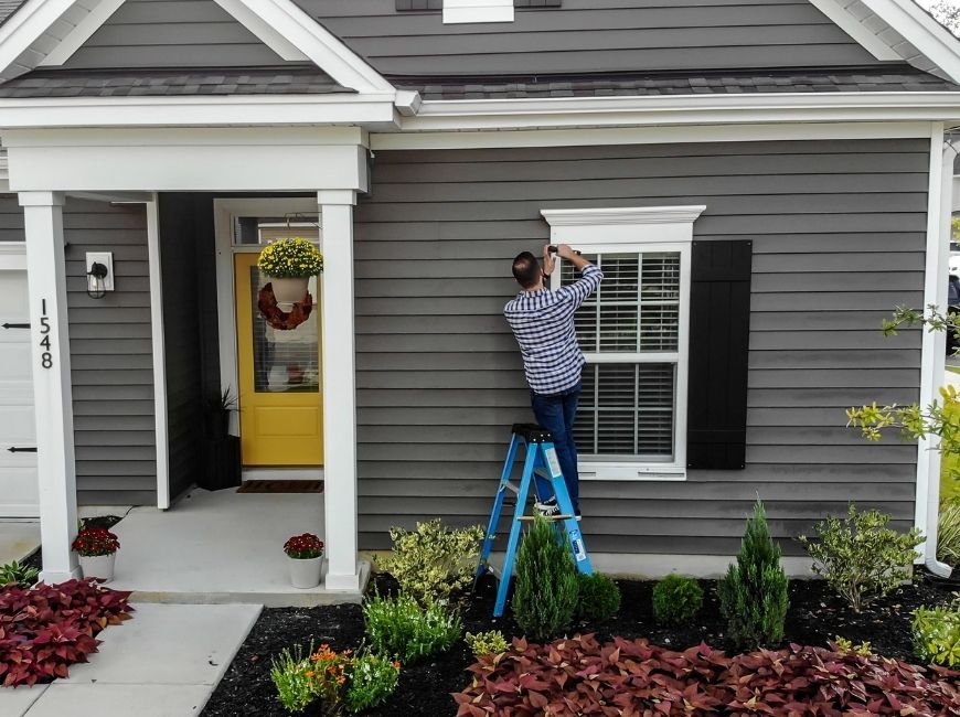 man installing shutters on house